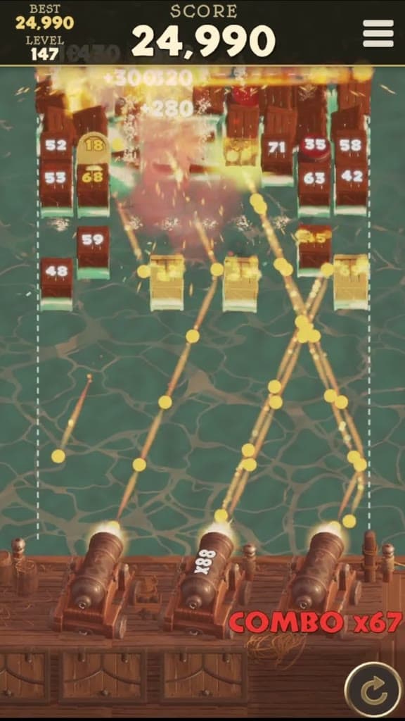 Cannonball Breakers gameplay at dawn: three cannons on the ship's deck fire golden shots into a wall of numbered crates as an explosion bursts among them, with a combo of 67